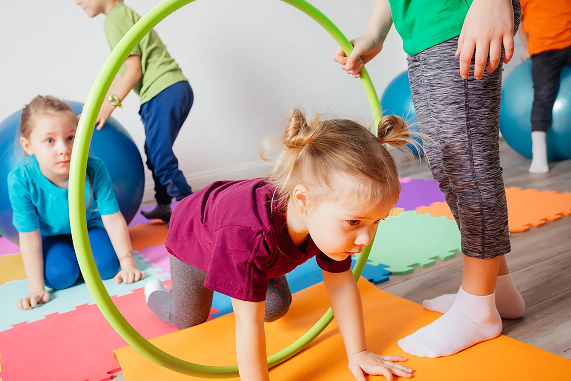 Enfants participant à un parcours de motricité avec cerceaux et tapis colorés
